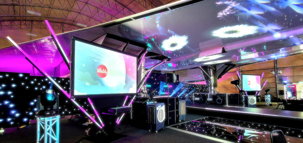 Projection screen at the Concorde Conference Centre with stage and lighting beneath the Concorde plane