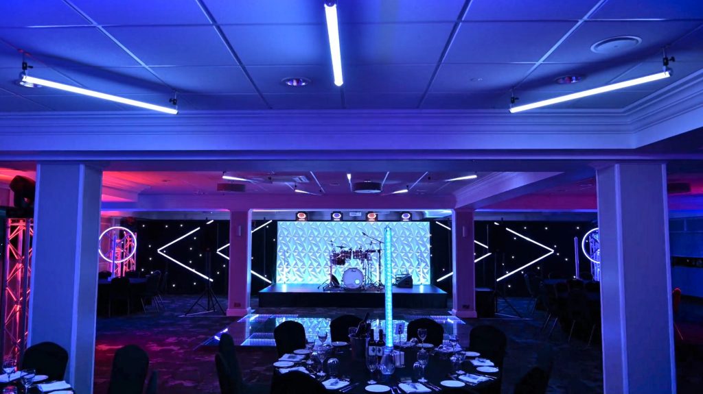 Futuristic-themed corporate event at the 1883 Suite in Stockport County Football Club with modern stage and lighting design